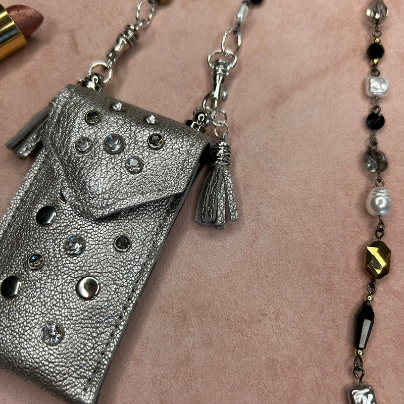 Close up of crystal embellishments & silver studs on silver leather pouch necklace.